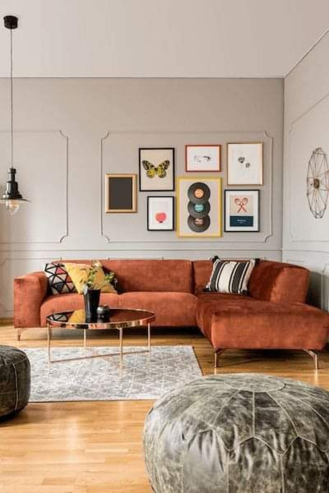 Living cu canapea de colț teracotă și perete gri cu panouri decorative din baghete