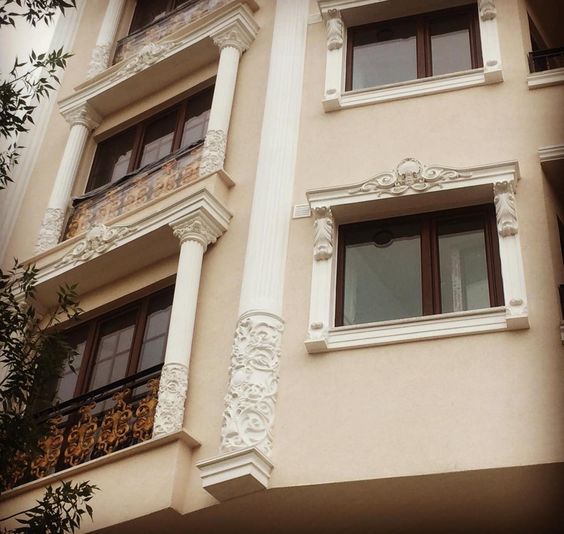 Fațadă crem cu coloane canelate albe, ancadramente de ferestre și frontoane decorative