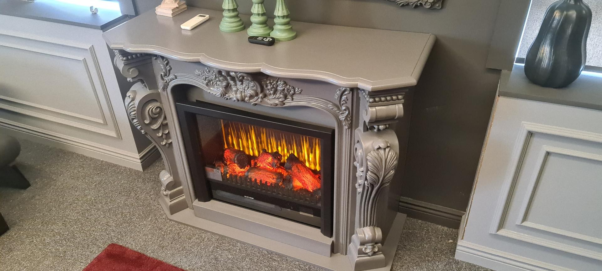 Semișemineu gri deschis cu foc electric și console sculptate, în showroom lambrisat