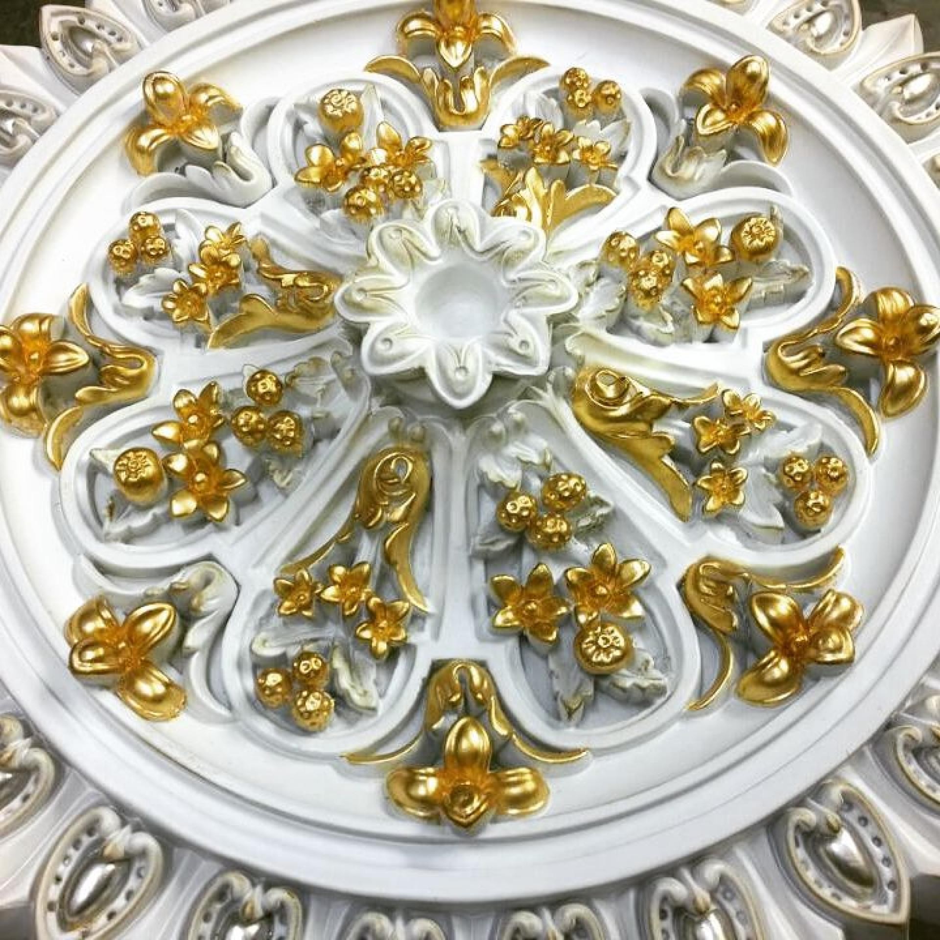 Rozetă de tavan albă cu flori aurite dispuse radial și cupă florală centrală