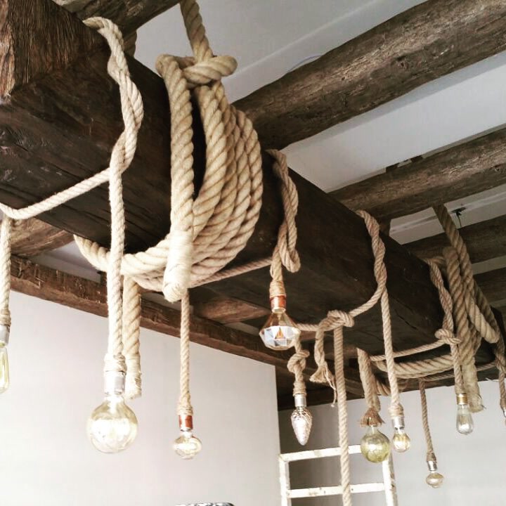 Grinzi de lemn aparente cu funii groase de cânepă și becuri decorative suspendate