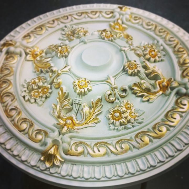 Rozetă de tavan verde mentă cu ghirlande florale aurite, așezată pe stativ în atelier