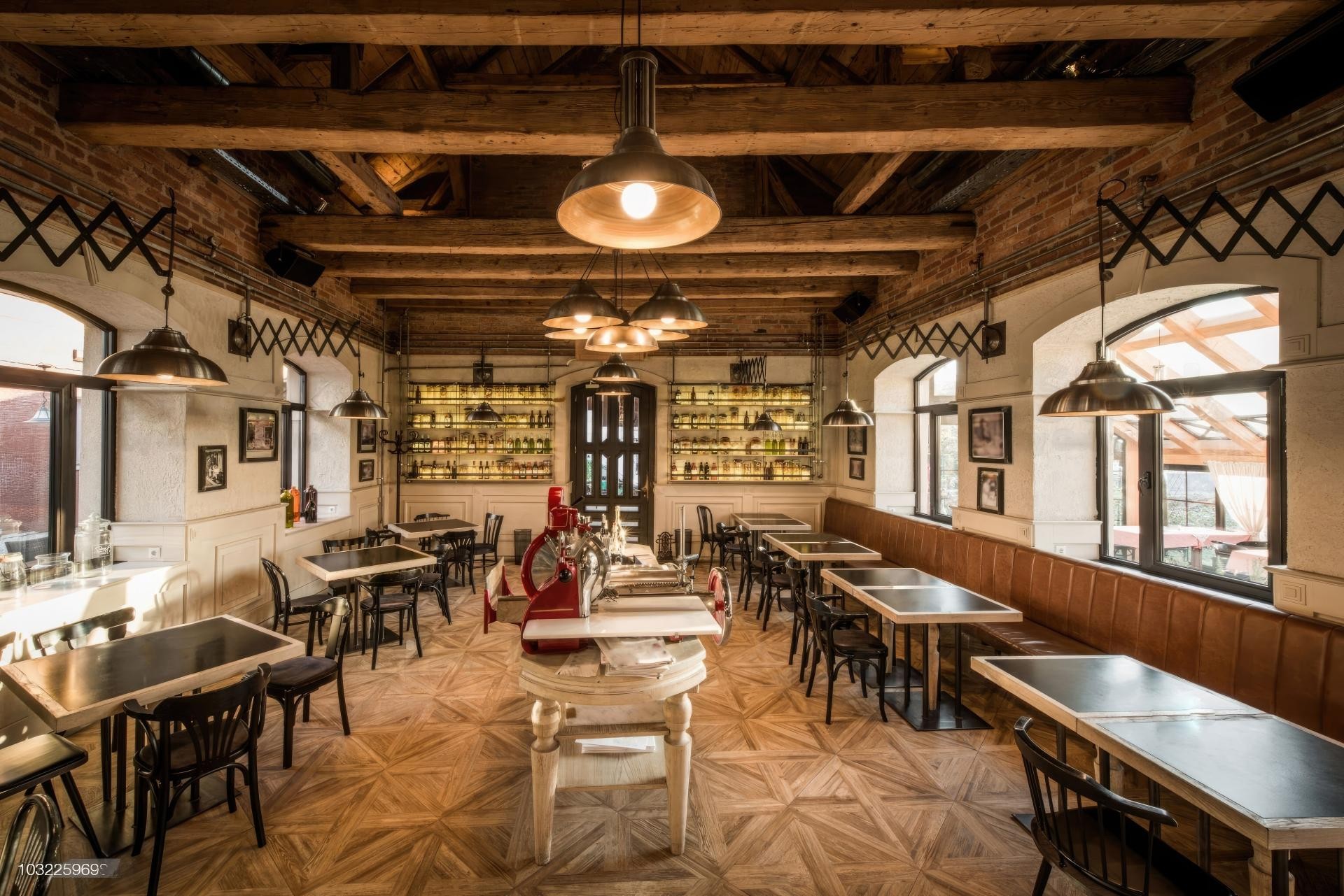 Sală de restaurant cu boiserie albă din poliuretan, tavan cu grinzi, lămpi industriale și banchetă din piele