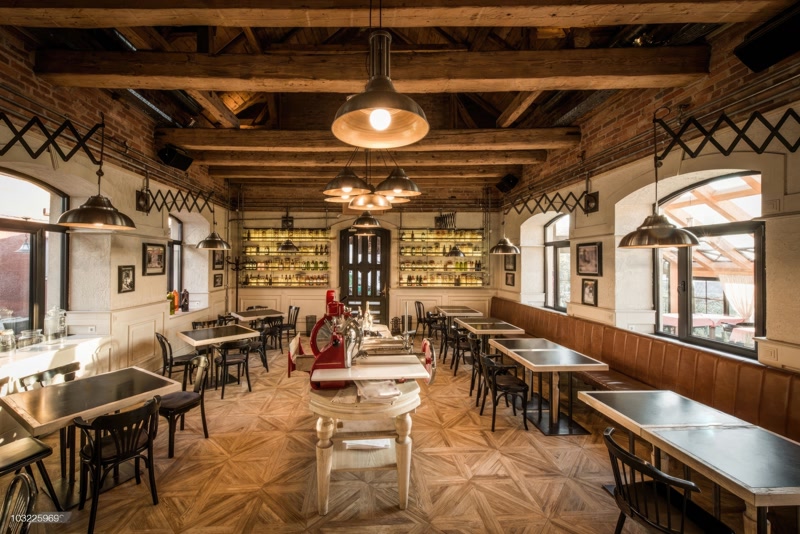 Sală de restaurant cu boiserie albă și tavan cu grinzi