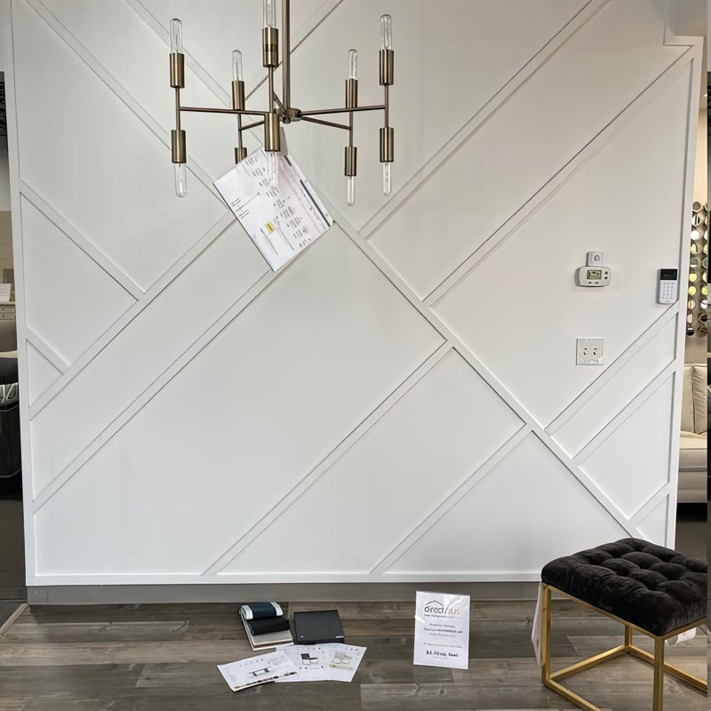 Perete alb cu profile decorative diagonale din poliuretan într-un spațiu de prezentare