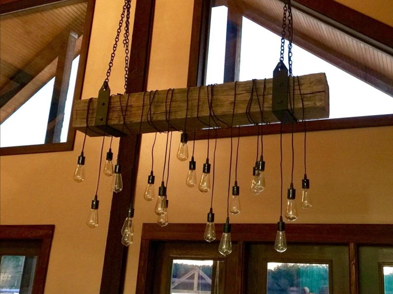 Candelabru cu becuri Edison pe grindă decorativă din lemn într-o mansardă