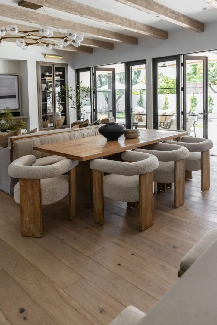 Zonă de dining open-space cu grinzi decorative din lemn deschis pe tavan alb