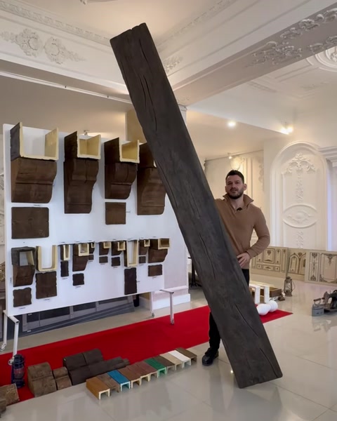 Bărbat lângă o grindă înaltă expusă în showroom cu mostre pe perete