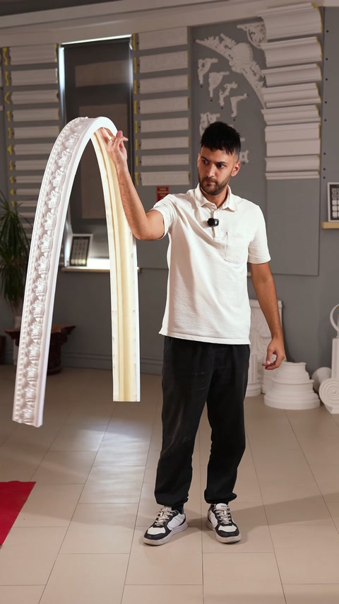 Meșterul prezintă în showroom un brâu flexibil curbat în formă de arc.