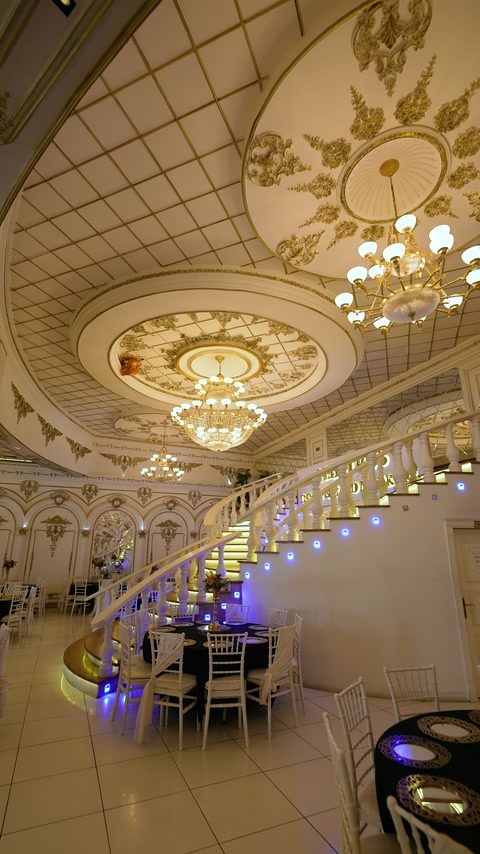 Tavanul sălii este accentuat de rozete ample și ornamente aurii.