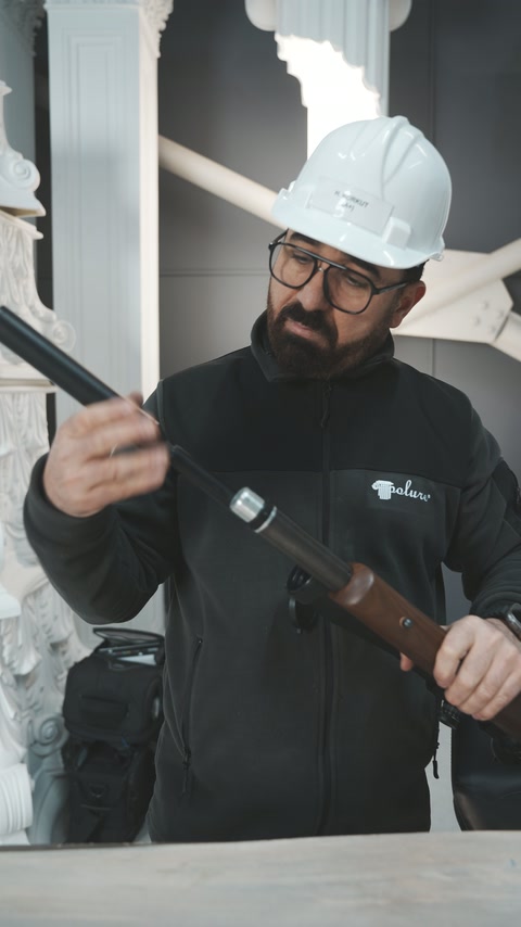 Operatorul manevrează pușca lângă grinda decorativă expusă pe masă.