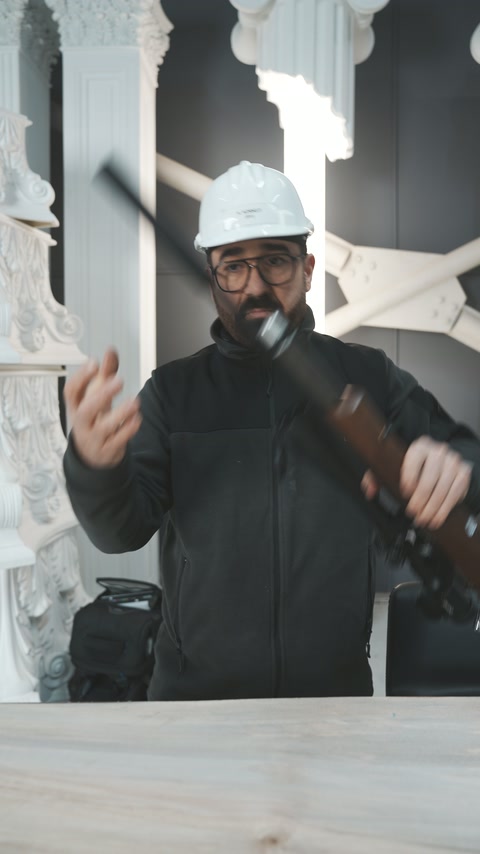 Bărbatul ridică arma pentru demonstrația realizată între coloanele ornamentale.