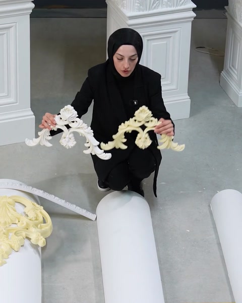Femeie în genunchi manipulează un profil lung flexibil cu model sculptat.
