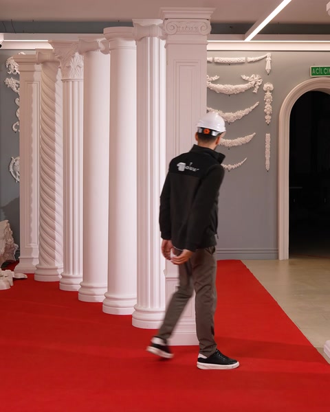 Bărbat traversează showroom spre perete cu ornamente și șemineu