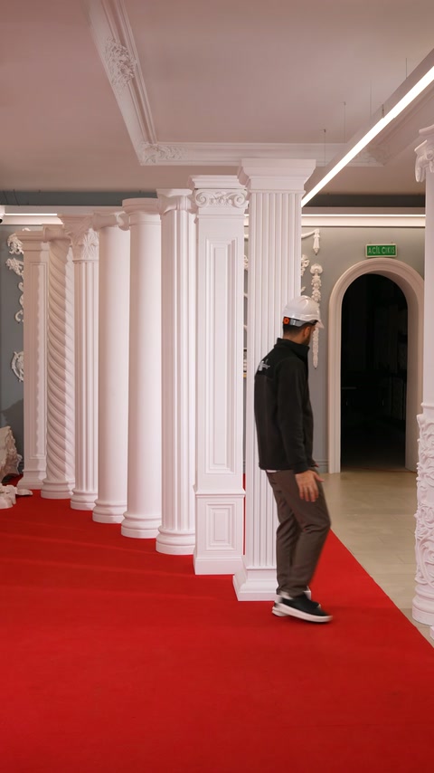 Lucrătorul trece pe lângă pilaștri și coloane aliniate în showroom.