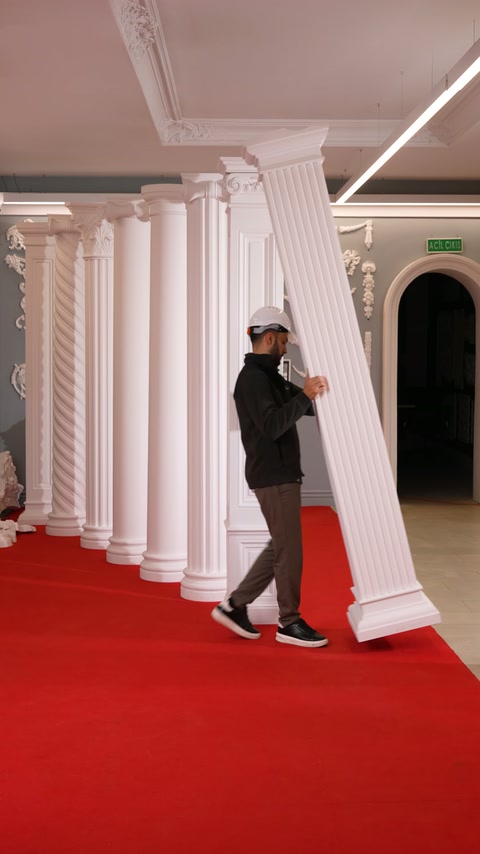 Lucrătorul înclină un pilastru canelat, pregătindu-l pentru repoziționare în expoziție.