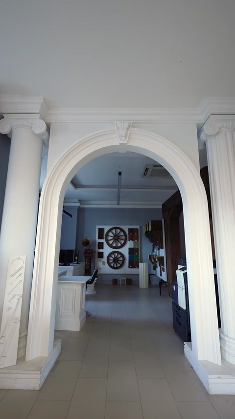 Ancadrament arcuit alb montat între coloane într-un spațiu interior.
