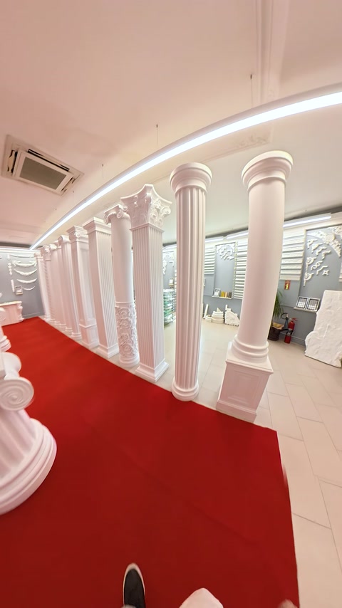 Colonada albă delimitează traseul interior acoperit cu mochetă roșie.