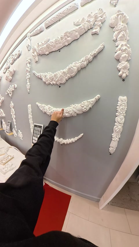 Panoul expozițional reunește ghirlande, rozete și ornamente florale albe.