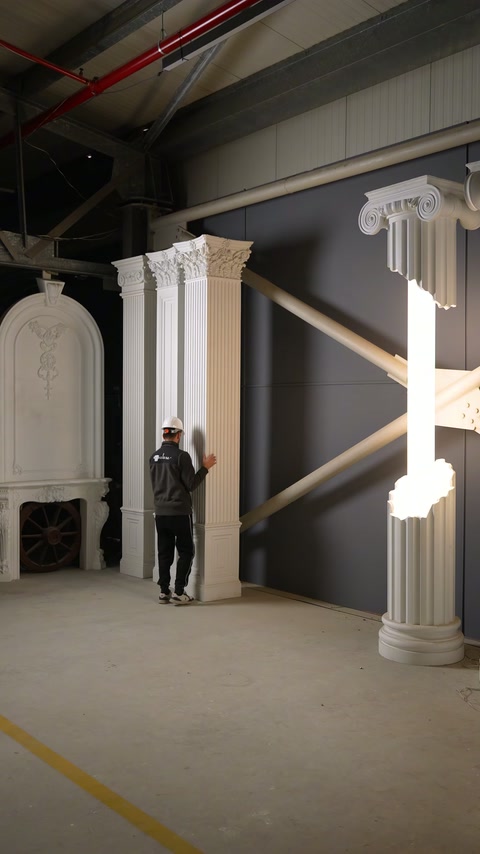 Muncitorul poziționează un pilastru pătrat lângă coloanele ornamentale expuse.