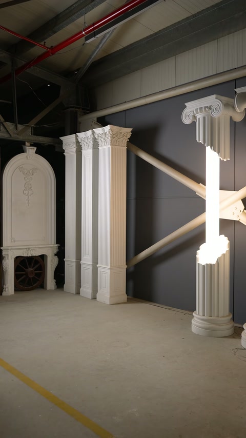 Trei pilastri monumentali prezintă capiteluri sculptate și baze geometrice.