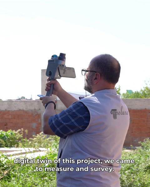 Bărbat ține scanerul 3D portabil pentru măsurarea fațadei clădirii