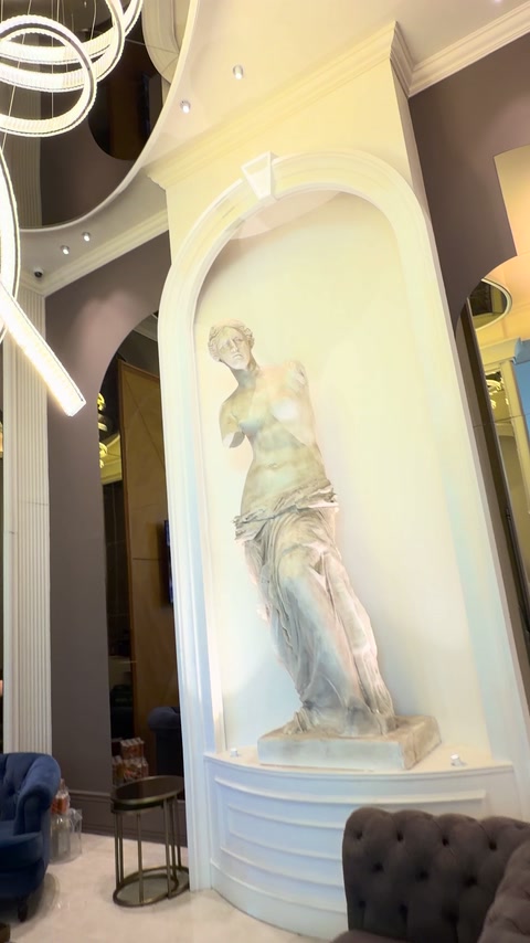 Arc decorativ alb care încadrează statuia din hol