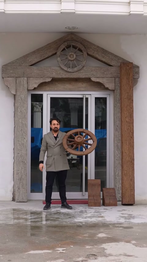 Prezentatorul ține ornamentul circular în dreptul intrării amenajate rustic.