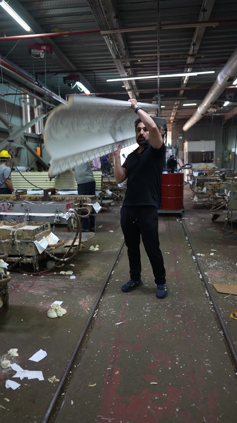 Operator ridicând o piesă curbată în hala de producție