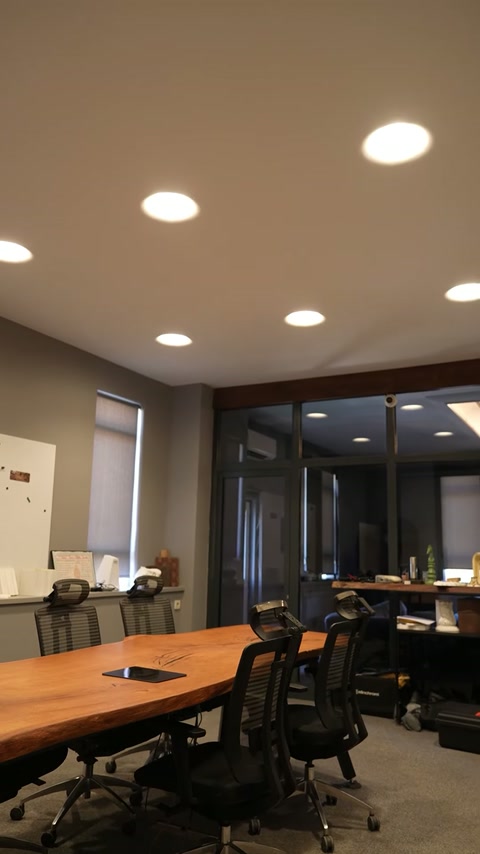 O perspectivă laterală surprinde spoturile distribuite deasupra scaunelor de birou.