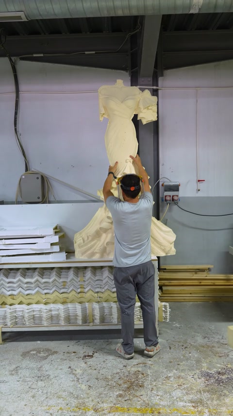 Muncitor manevrează un element decorativ mare lângă utilajul CNC