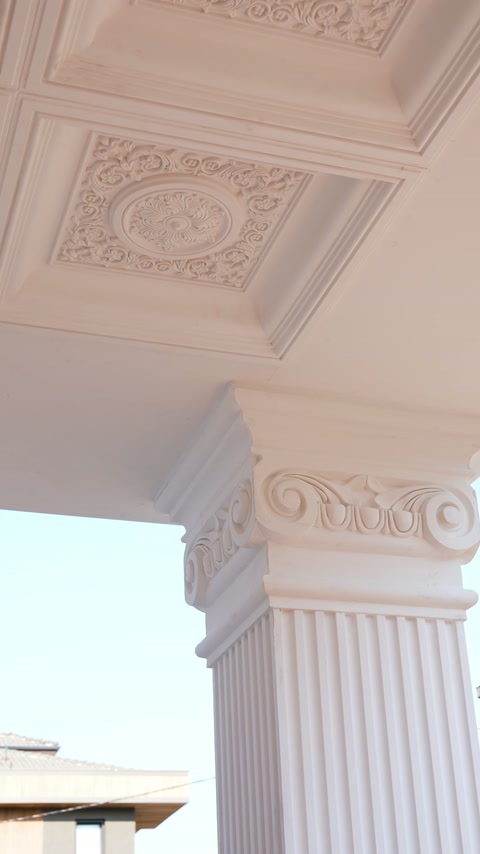 Capitelul ornamental încheie elegant coloana canelată a porticului.